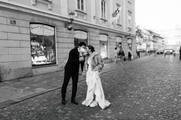 Bride and groom kissing on a cobblestone street in Ljubljana old town, black and white wedding photo